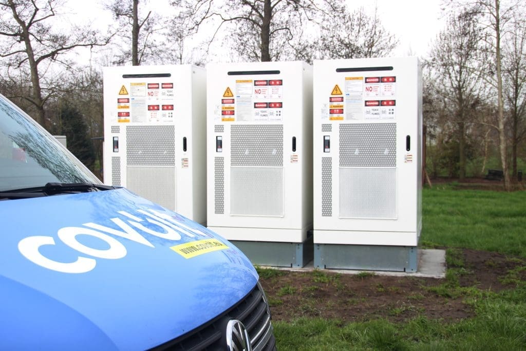Covolt servicemonteur naast drie batterijopslag-units (BESS) op een buitenlocatie in België